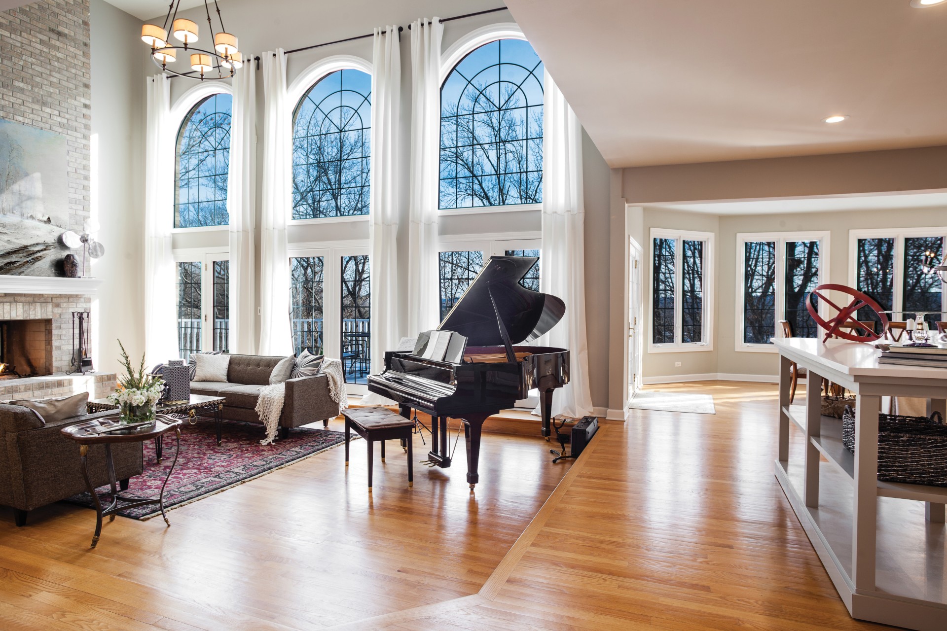 Light-filled living room with tall arched windows and a grand piano